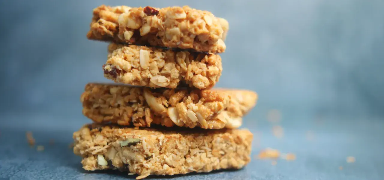 Stack of oat and nut granola bars against a blue background.