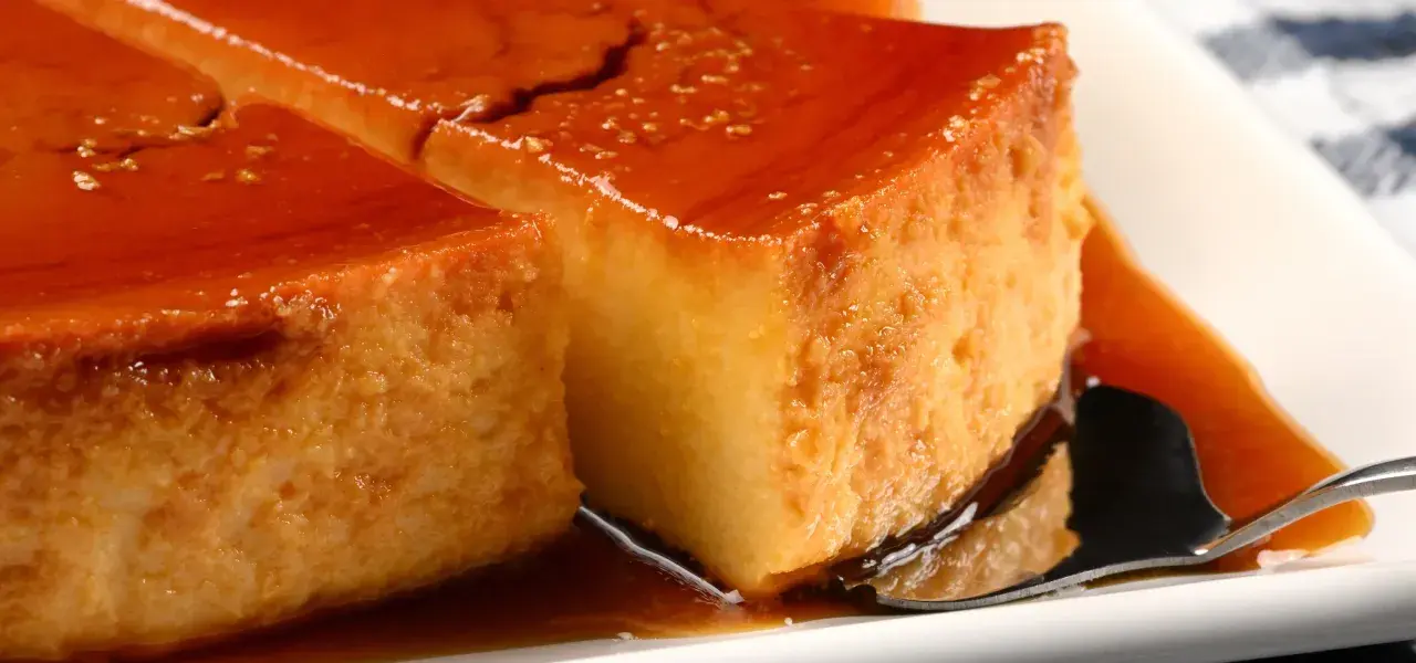 Sliced caramel flan custard dessert on a white plate.