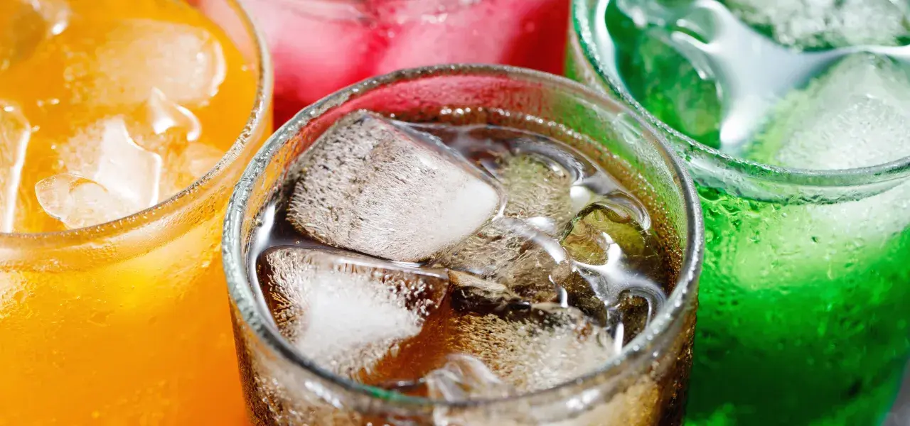 Colorful carbonated soft drinks with ice in glasses.