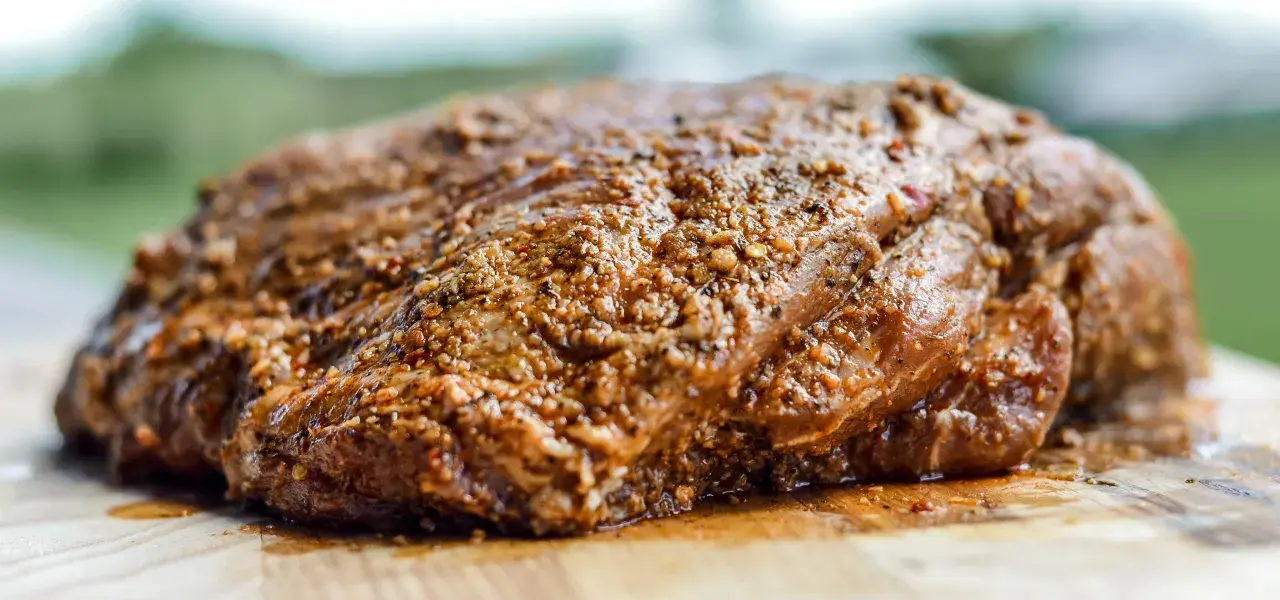 Seasoned roast beef with a peppercorn crust on a cutting board.